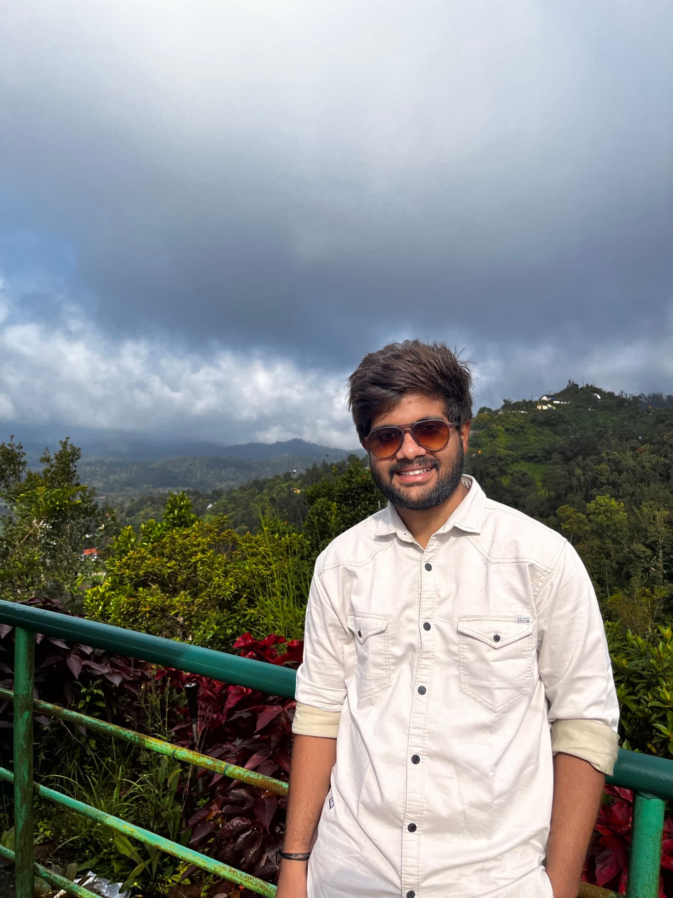 Mohit smiling in front of mountain clouds